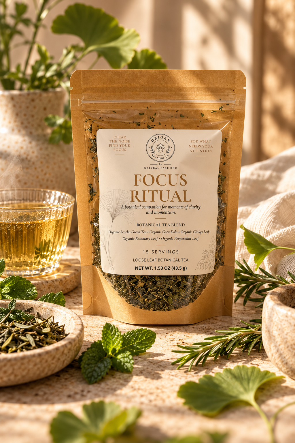Focus Ritual kraft pouch in warm sunlight with a glass of green tea, loose tea, mint and rosemary
